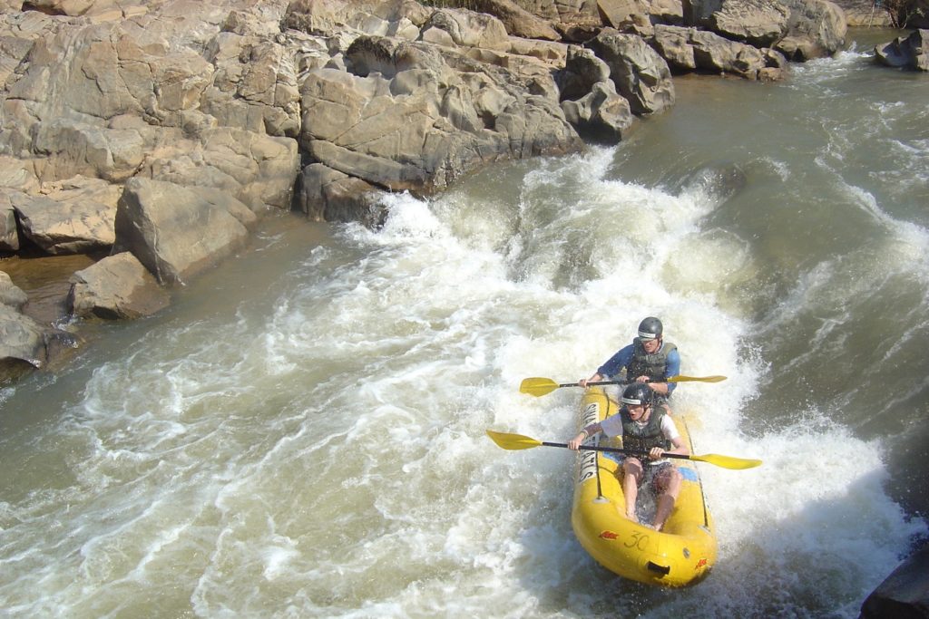 Two kayakers navigate a rough river