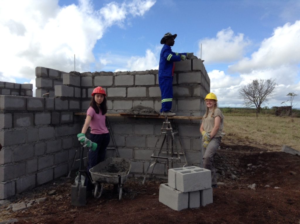 Three volunteers stop for a photo building an old age home 