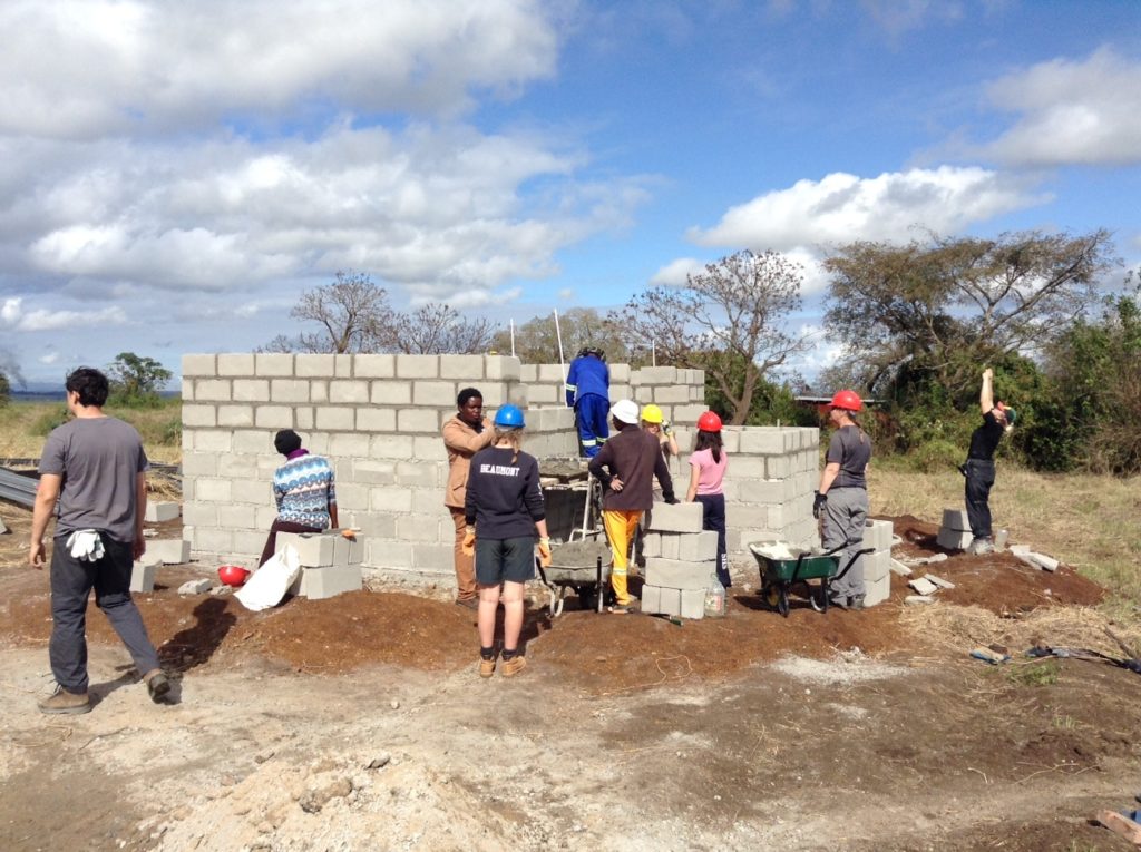 A group of volunteers work together on a building