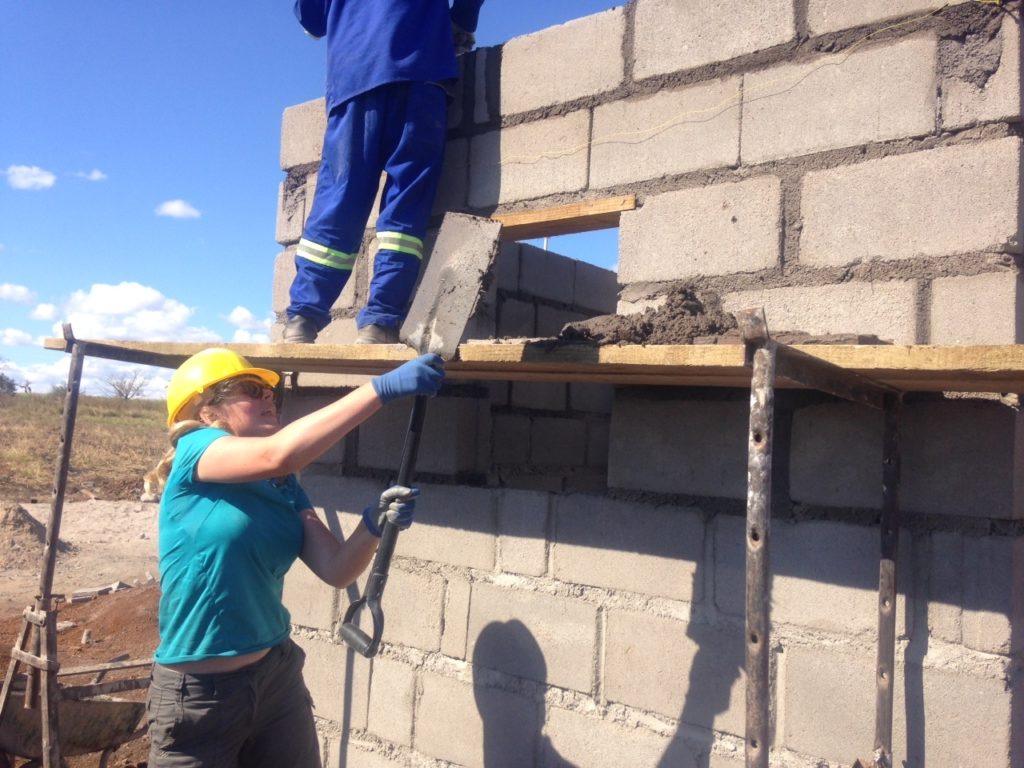 Two volunteers working on a wall building an old peoples home